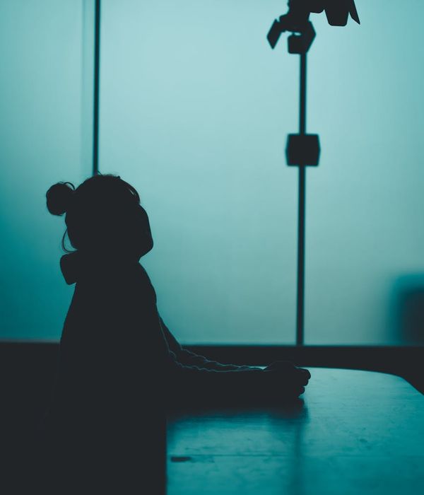 Woman in a calm, balanced pose against a dark background with citron light.